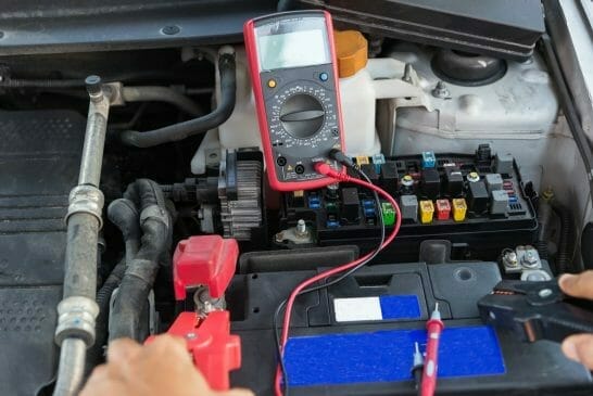 mechanic testing car engine with multimeter