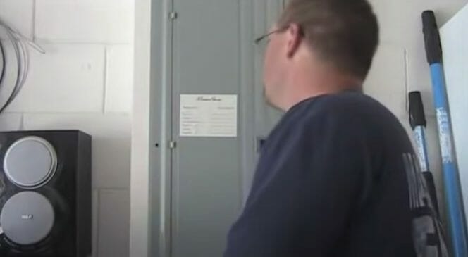 A person standing in front of a main circuit panel