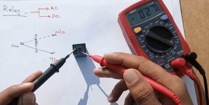 a person testing the coil terminals with a multimeter