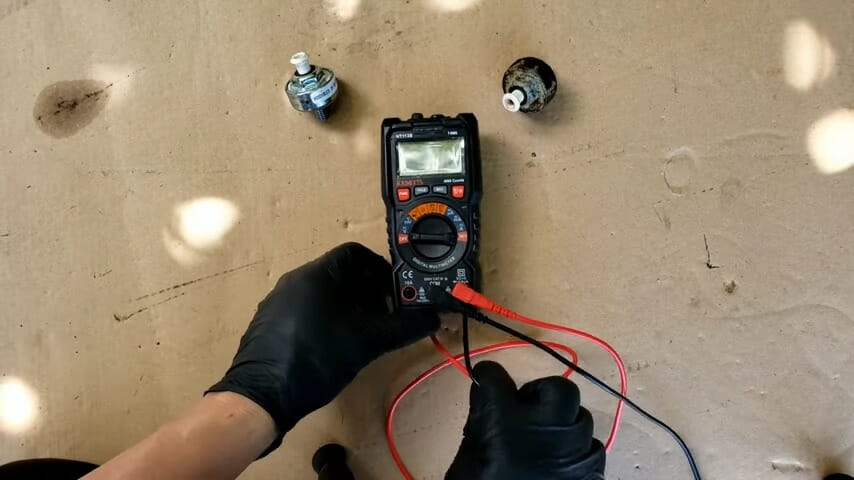 mechanic in black gloves checking the reading on the multimeter