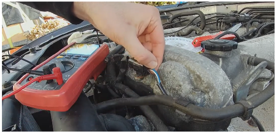 man testing air fuel sensor with multimeter