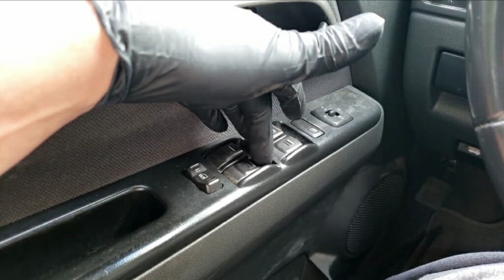 driver with black glove pressing buttons at the driver's window side