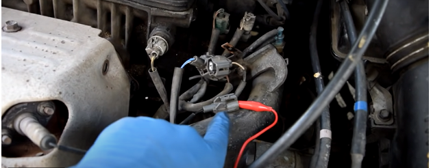 man in blue gloves connecting multimeter leads to signal voltage wire