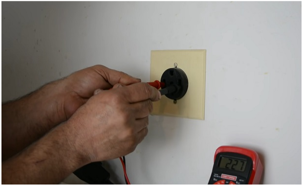 man testing outlet with multimeter