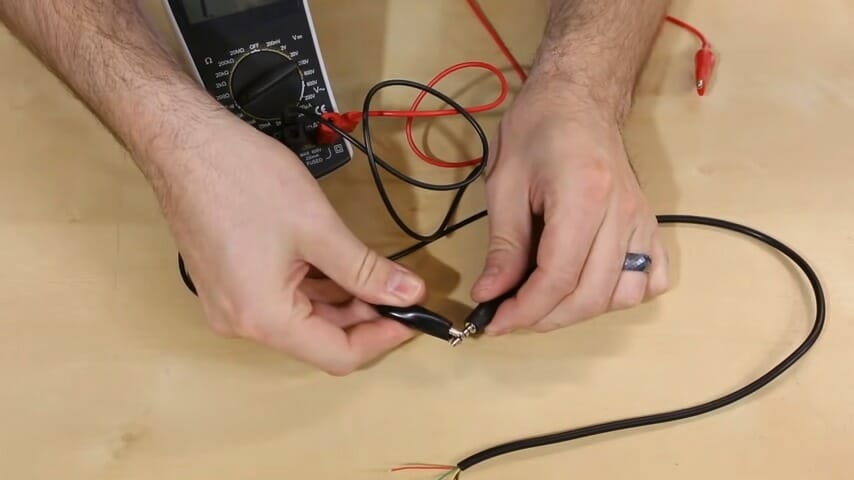 man holding a multimeter tweezer probes 