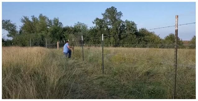 man working on the barbed wire fence in a farm