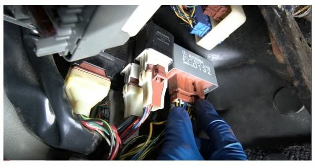 A person wearing a blue gloves locating and accessing fuel pump