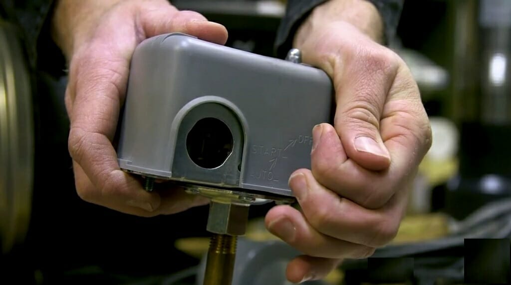 man's hand locating the well pressure switch
