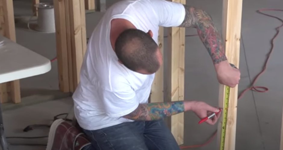 electrician marking the studs using tape measure and pen