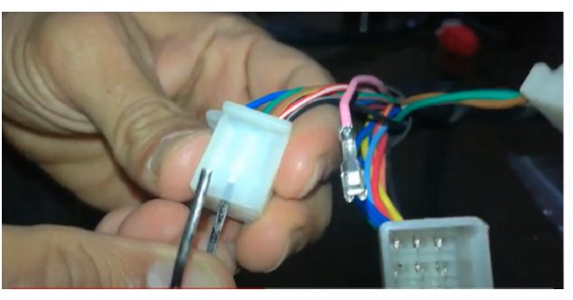 swinging the clip up and out of a hole on the nose of the metallic terminal