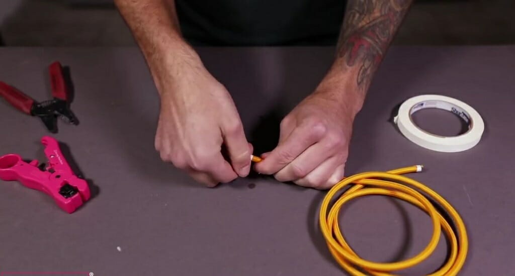 using the box cutter to remove the marked cloth cover of the cord