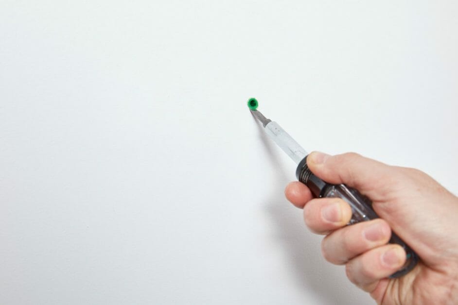 close to the nail’s head on the wall