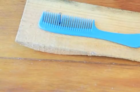 A comb on a nail and piece of wood