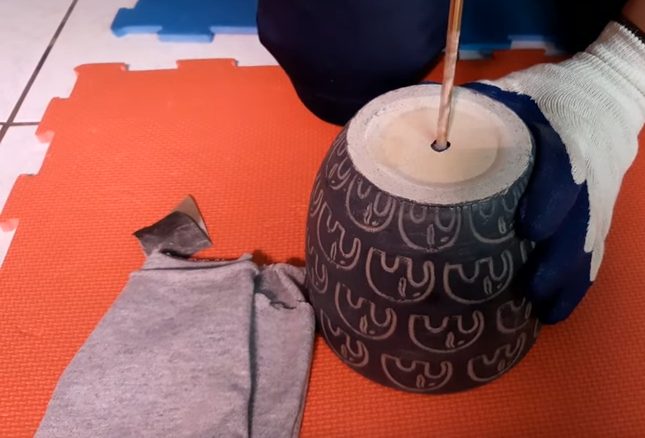 a person with white gloves is drilling ceramic pot