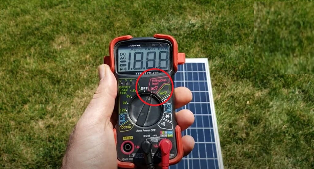 A man holding a multimeter with a solar panel on the grass