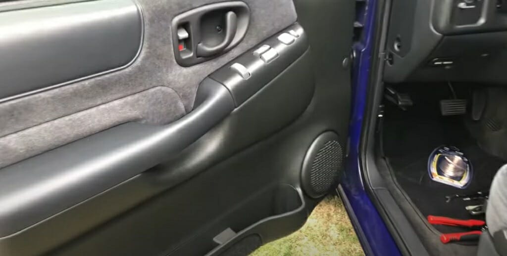 An open driver's door of a car with plier on the floor