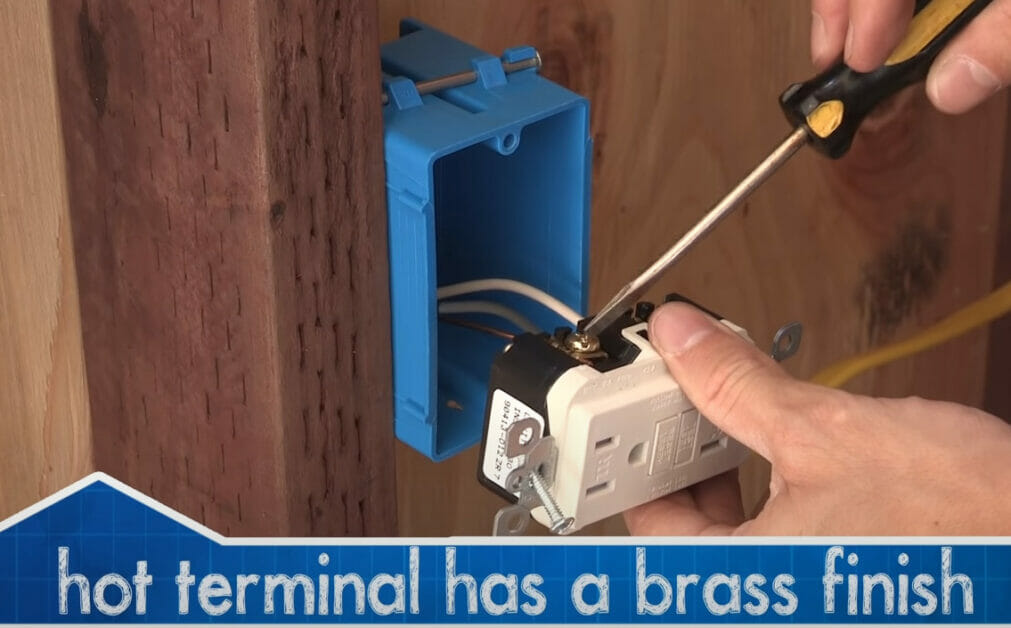 A person attaching the hot wire to the outlet's right terminal using screwdriver