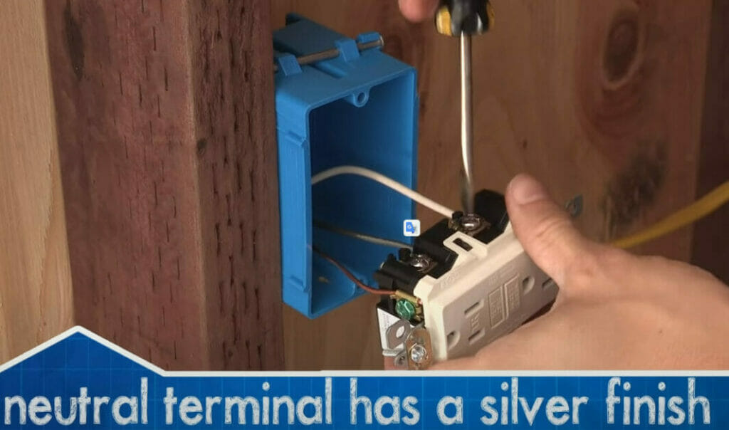 A person attaching the neutral wire to the outlet's right terminal