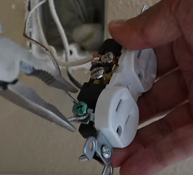 A person attaching the ground wire to the green terminal