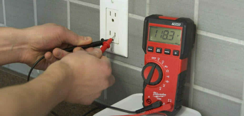 A person testing a GFCI outlet with a multimeter