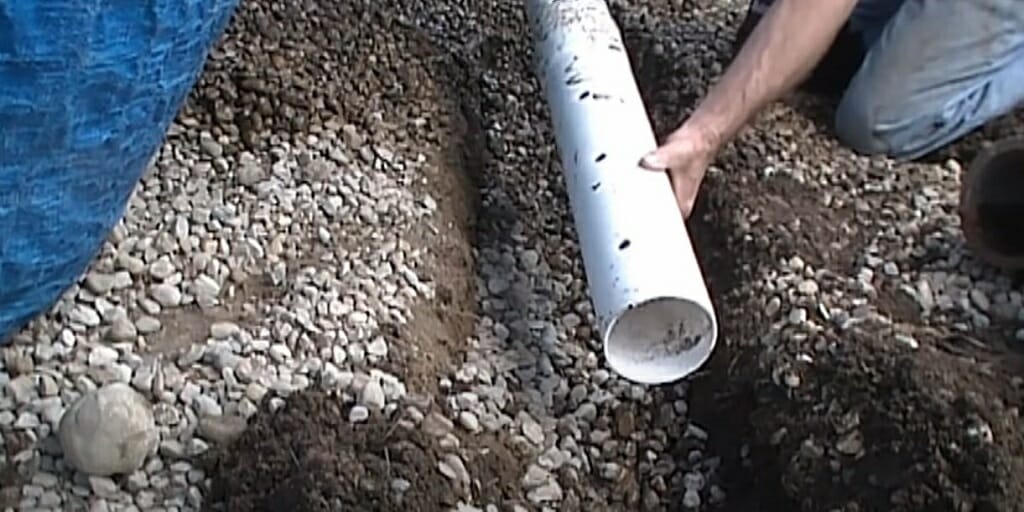 a man's hand holding a perforated pipe