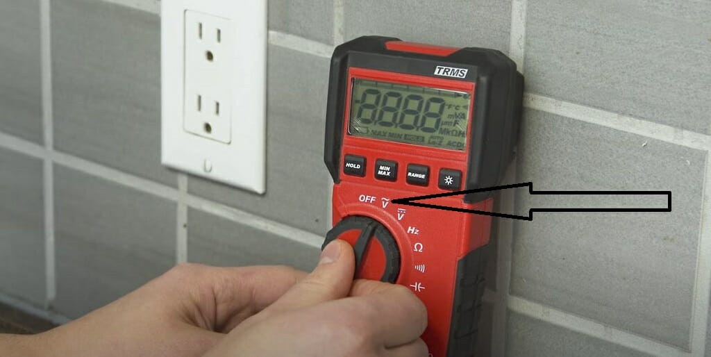 A person is setting up the multimeter before testing a wall outlet