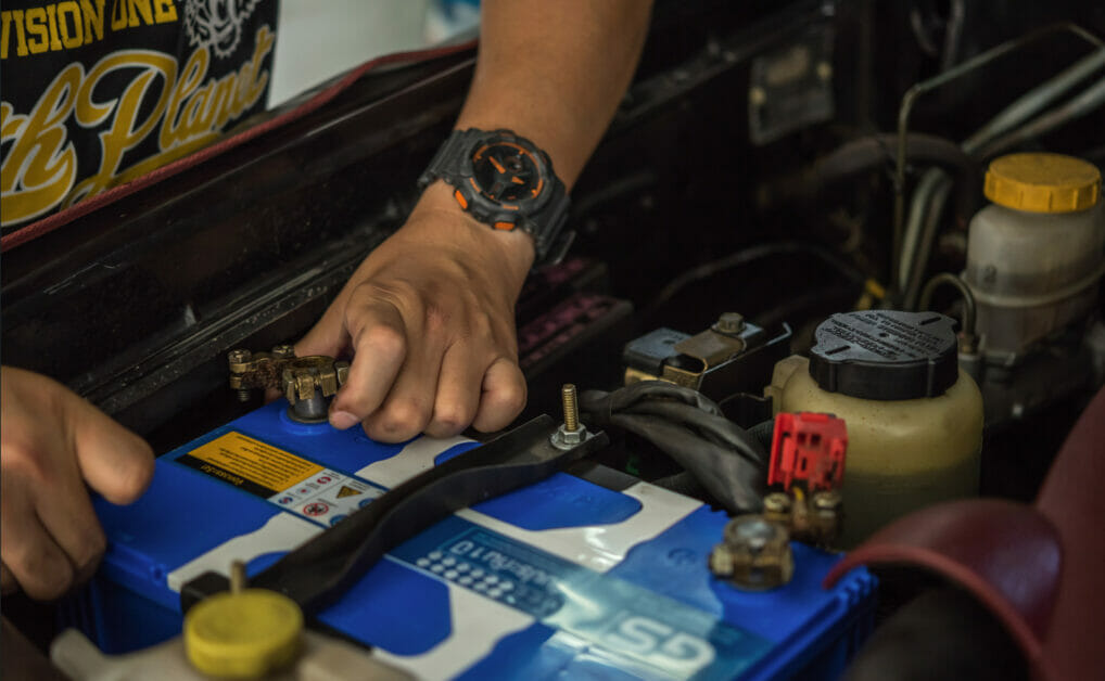 man reconditioning his car battery