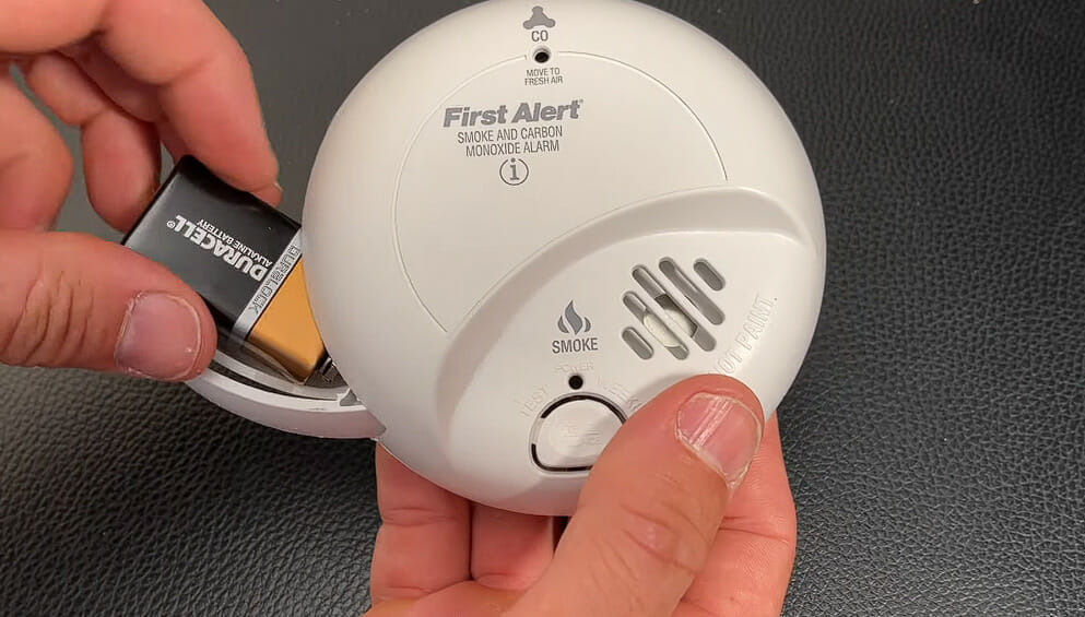 man taking out the battery of a smoke detector