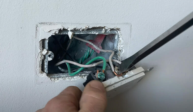 A person is loosening the screw on the terminal using a screwdriver