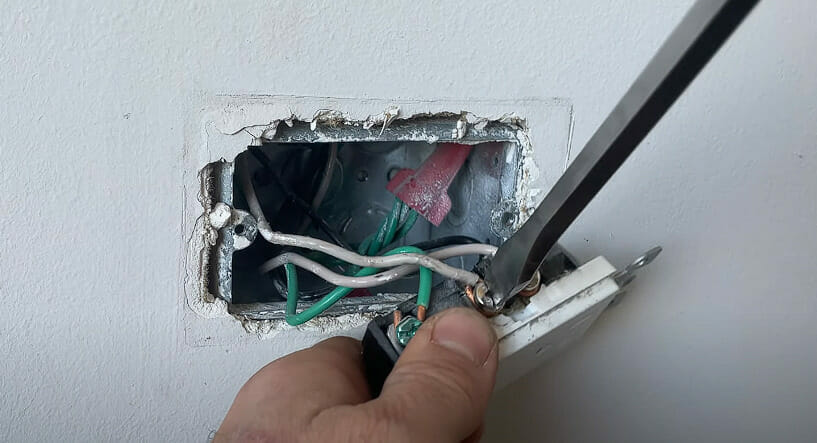 A person tightening up the terminal with screw