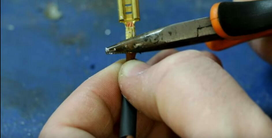 A person is using pliers to cut and crimp a wire