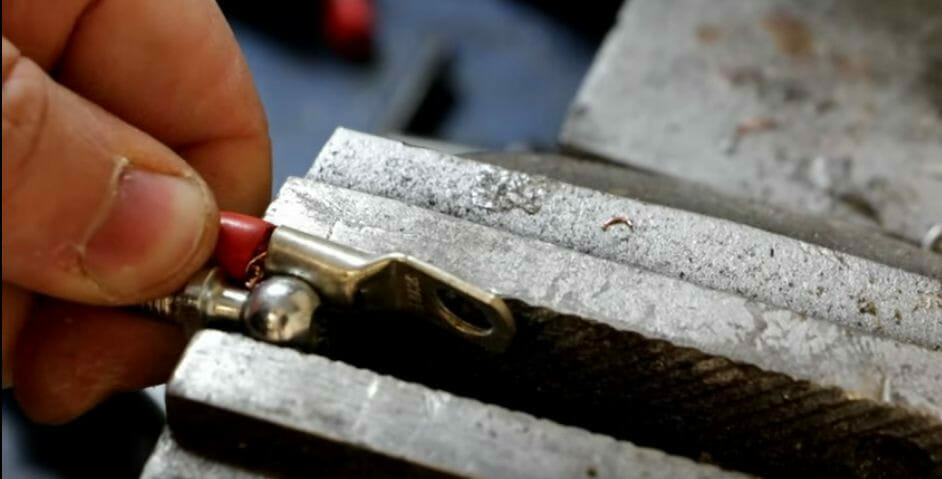 A person using a clamp or vise to crimp a wire