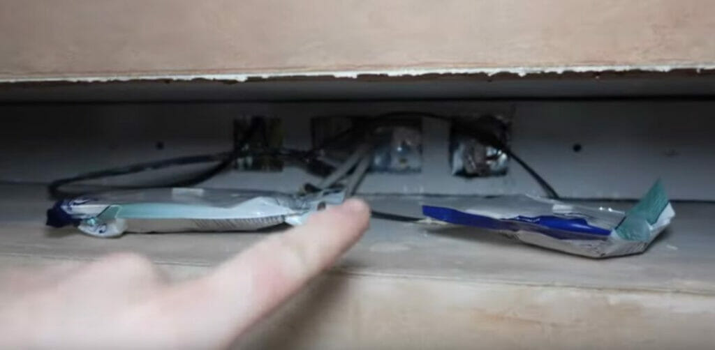 A person is pointing to an electrical outlet in a kitchen