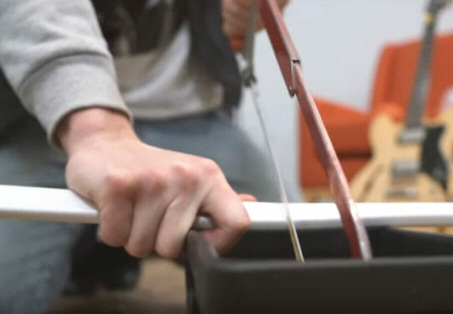 A person is using a small saw to cut conduit