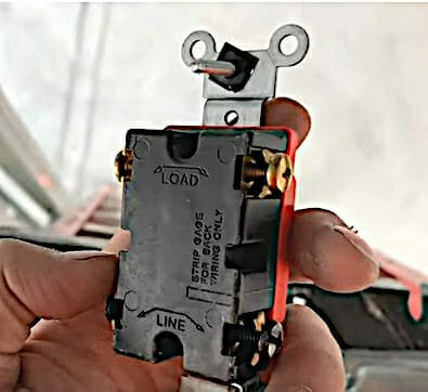 A man's hand holding a switch showing its back