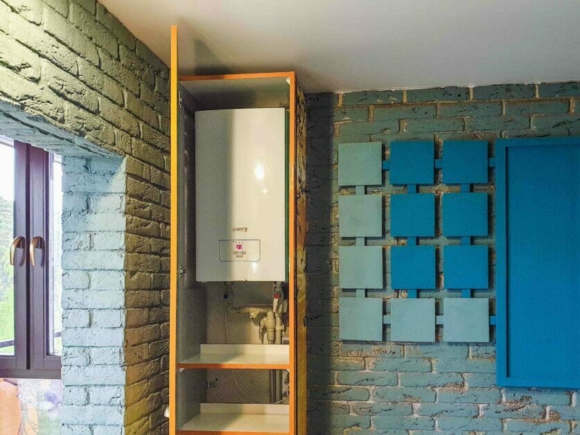 A water heater installed on a stone wall with shelve