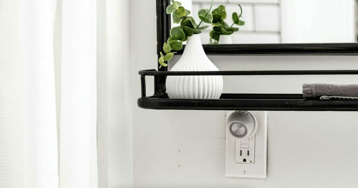 A GFCI outlet under a shelf in the bathroom