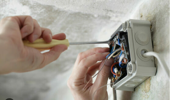 A person is screwing an open wire box with wires