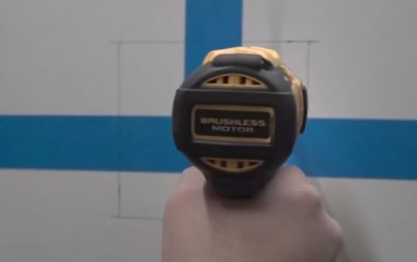 A person drilling a pilot hole into the marked wall