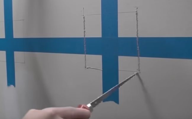 A person using a power drill to drill the wall