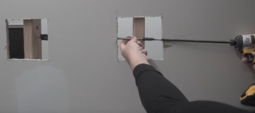 A person using a power drill to drill the wall