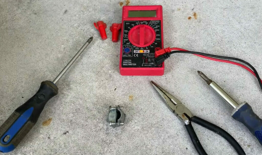 A pair of pliers, cutter and multimeter on a concrete floor