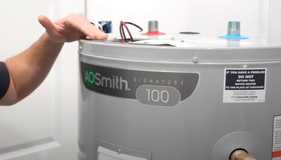 A person touching the top of a water heater