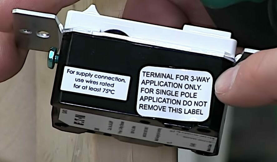 A person is holding an adaptable 3-way dimmer switch