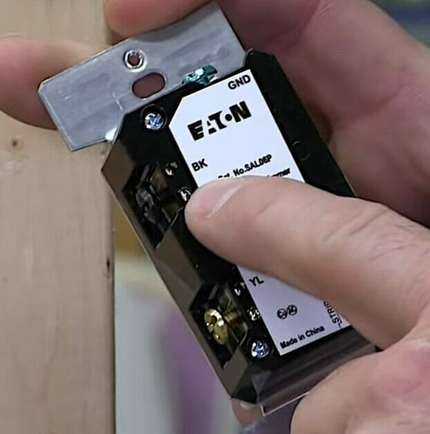 A person holding a COM/Black terminal on a 3-way dimmer switch