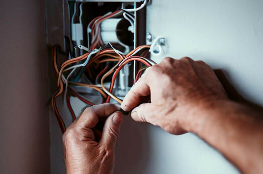 A man fixing a wire on a breaker box