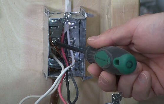 A person grounding the wires of an electrical box