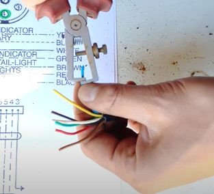 A person measuring a wire for trailer plug