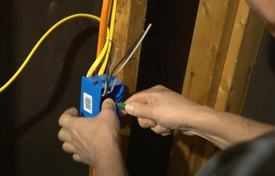 A person performing a tug test on the wire in a blue box