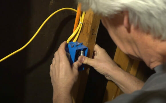 A man securely tuck wires at the blue box